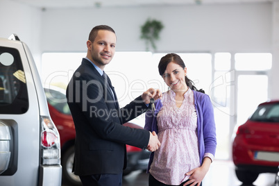 Salesman shaking hand and giving keys to a woman