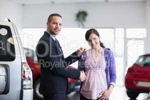 Salesman shaking hand and giving keys to a woman