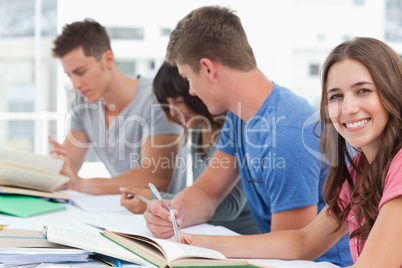 A side view of people studying as one girl looks into the camera