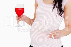 Young pregnant  woman holding a cocktail and a cigarette