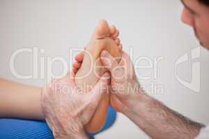 Podiatrist practicing reflexology on the foot of woman