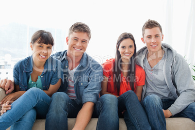 Smiling group on the couch looking at the camera while leaning f
