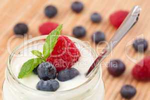Close up of a pot yoghurt with mint blueberries and raspberry