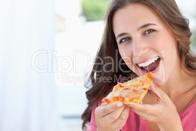 A woman with a pizza slice at her lips