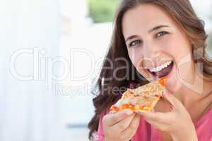 A woman with a pizza slice at her lips