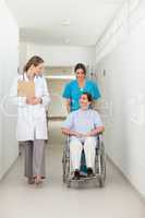 Nurse pushing a patient in a wheelchair while talking to a docto