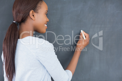 Black woman writing on a blackboard while smiling