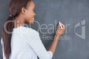 Black woman writing on a blackboard while smiling