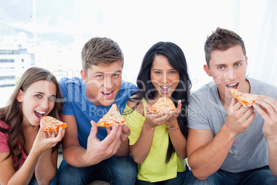 People about to eat pizza as they look at the camera