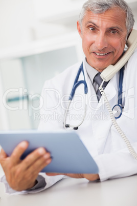 Smiling doctor holding a tablet computer and calling