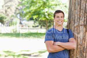 Portrait of a muscled student leaning against a tree