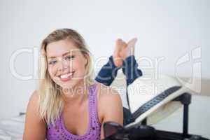 Young blonde smiling behind a suitcase