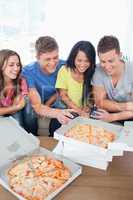 A laughing group of friends gathered around some pizza