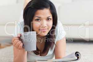 Woman holding a mug on the floor while reading