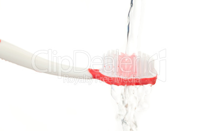 Water falling on a red toothbrush