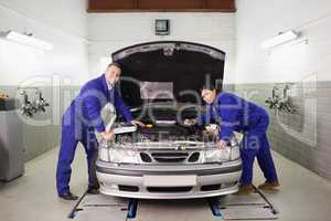 Mechanics leaning on a car looking at camera