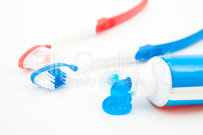 Two toothbrushes next to a tube of toothpaste