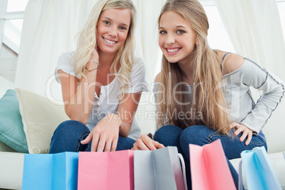Smiling girls looking at the camera with bags by their feet