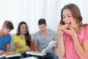 A woman about to eat a slice of pizza with her friends behind he