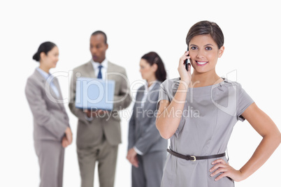 Woman smiling on the phone with co-workers in the background