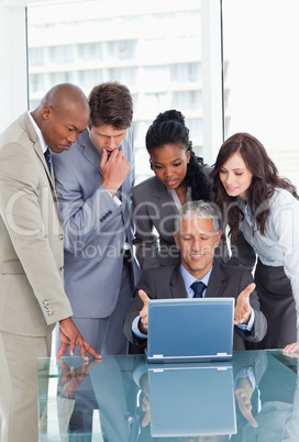 Mature manager proudly showing the computer screen to his team