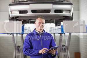 Smiling mechanic touching a tablet computer