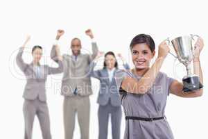 Woman holding up a cup with enthusiastic co-workers