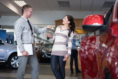 Salesman holding paper and giving keys to a woman