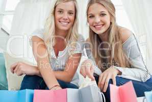 Girls smiling as they look at the camera with bags