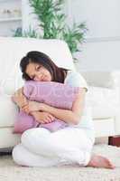 Woman looking sad while holding a pillow