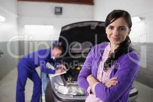 Woman with arms crossed next to a car