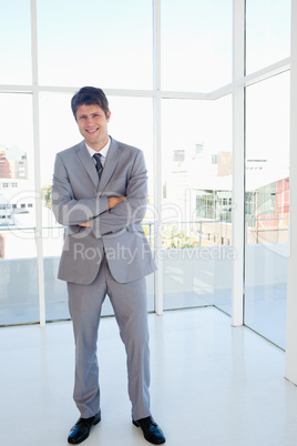 Laughing businessman crossing his arms while standing in a well