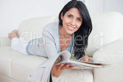 Woman holding a magazine while laying on a couch