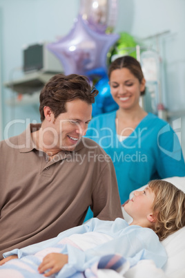 Child lying on a medical bed looking at his father