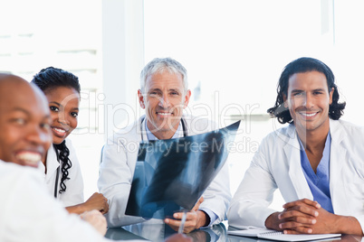 Mature doctor surrounded by three colleagues holding an x-ray of
