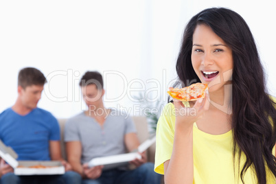 Smiling woman about to eat some pizza with her friends in the ba