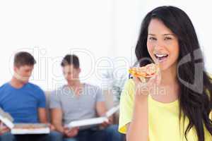 Smiling woman about to eat some pizza with her friends in the ba