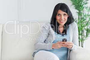 Woman holding a telephone while resting on a couch