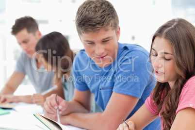 Side view of people studying as one guy helps a girl