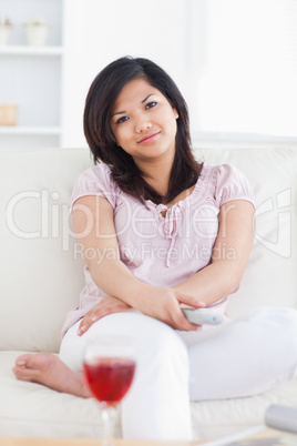 Woman holding a television remote while crossing her arms and le