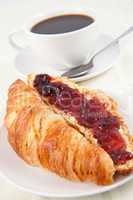 Coffee cup behind a croissant