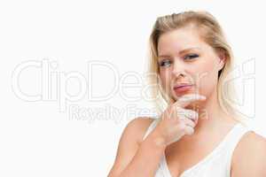Serious blonde woman placing her hand on her chin