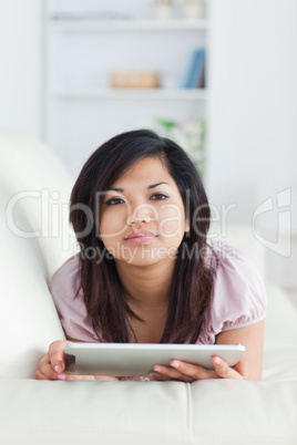 Woman lays on a sofa and plays with a tablet