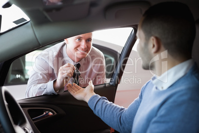 Smiling salesman giving keys to a customer