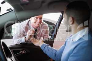 Smiling salesman giving keys to a customer