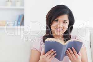 Woman sitting on a couch while holding a book