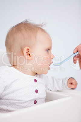 Beautiful little girl being fed with a spoon
