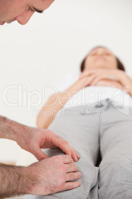 Woman lying on her back while a physiotherapist massing her knee