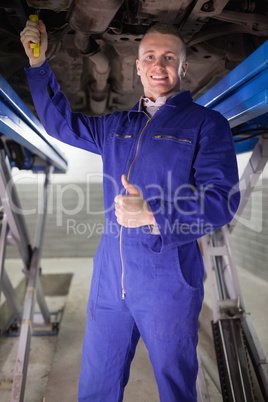 Man repairing a car with his thumb up