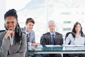 Confident executive sitting in a meeting room while her team is